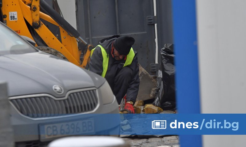 Работник с чук чупи на малки парчета жълти павета на