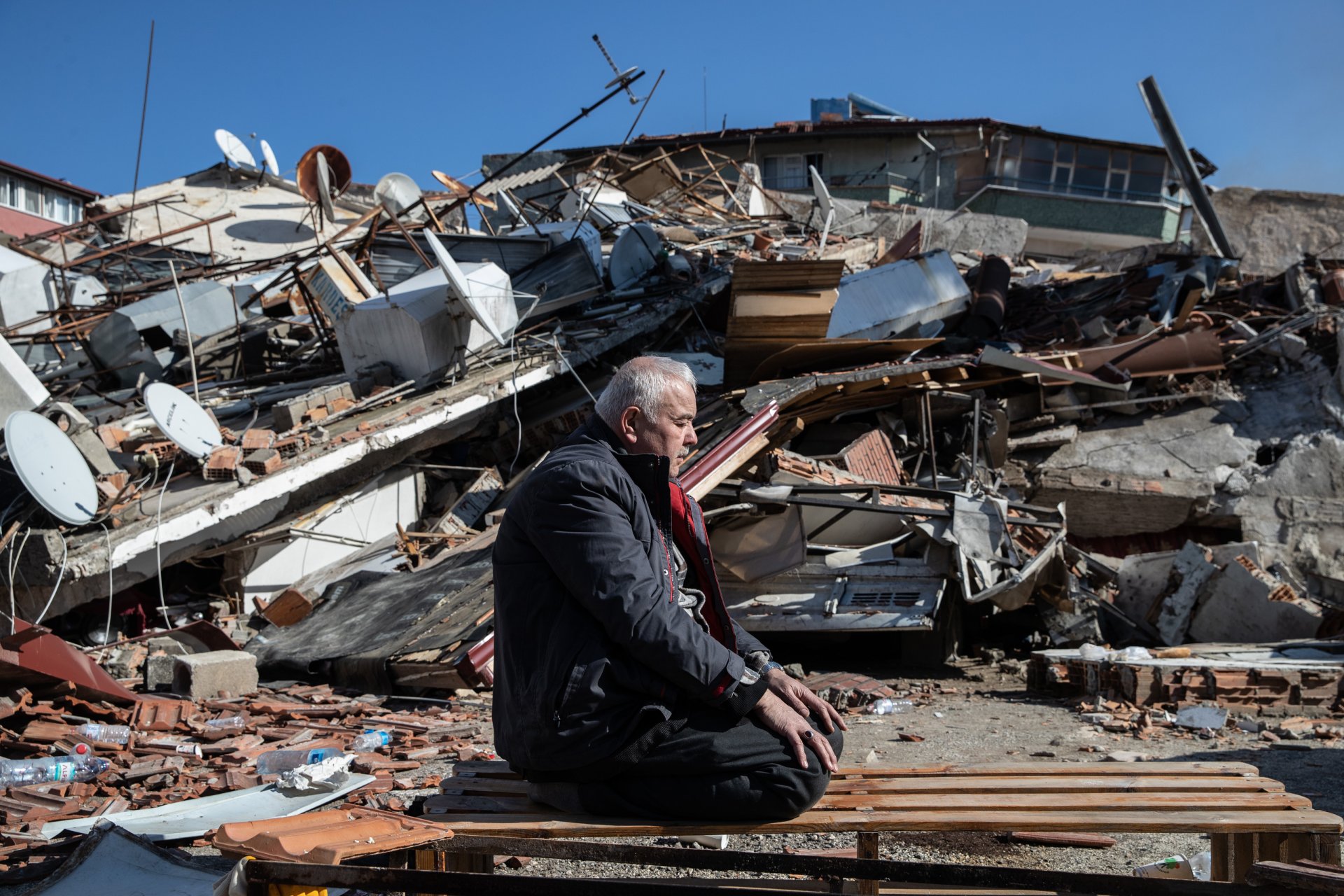 Мъж се моли пред срутена сграда