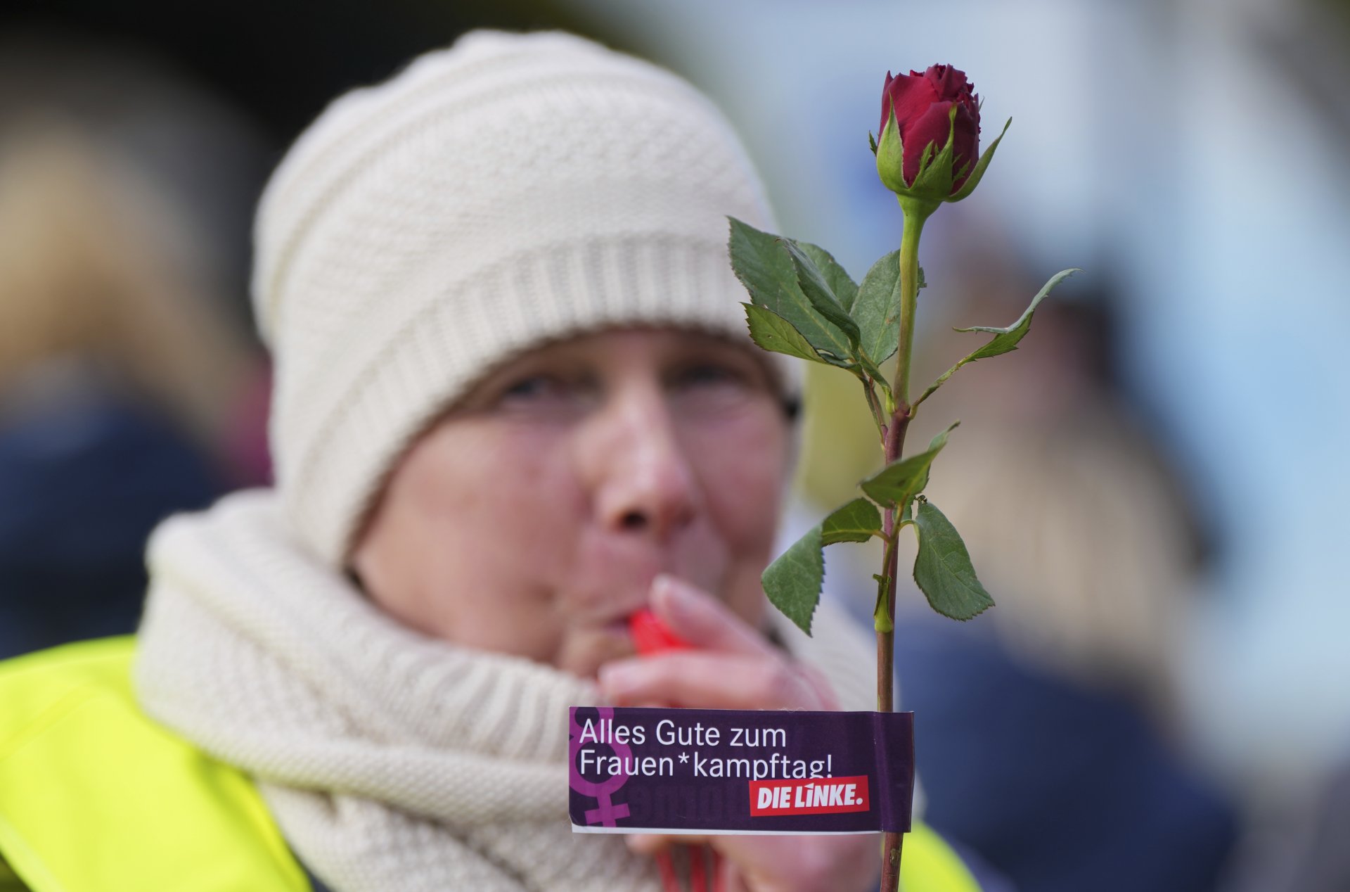 Участничката в демонстрация за Международния ден на жената държи роза с послание "Честит ден на борбата на жените!" в Хенингсдорф, Германия