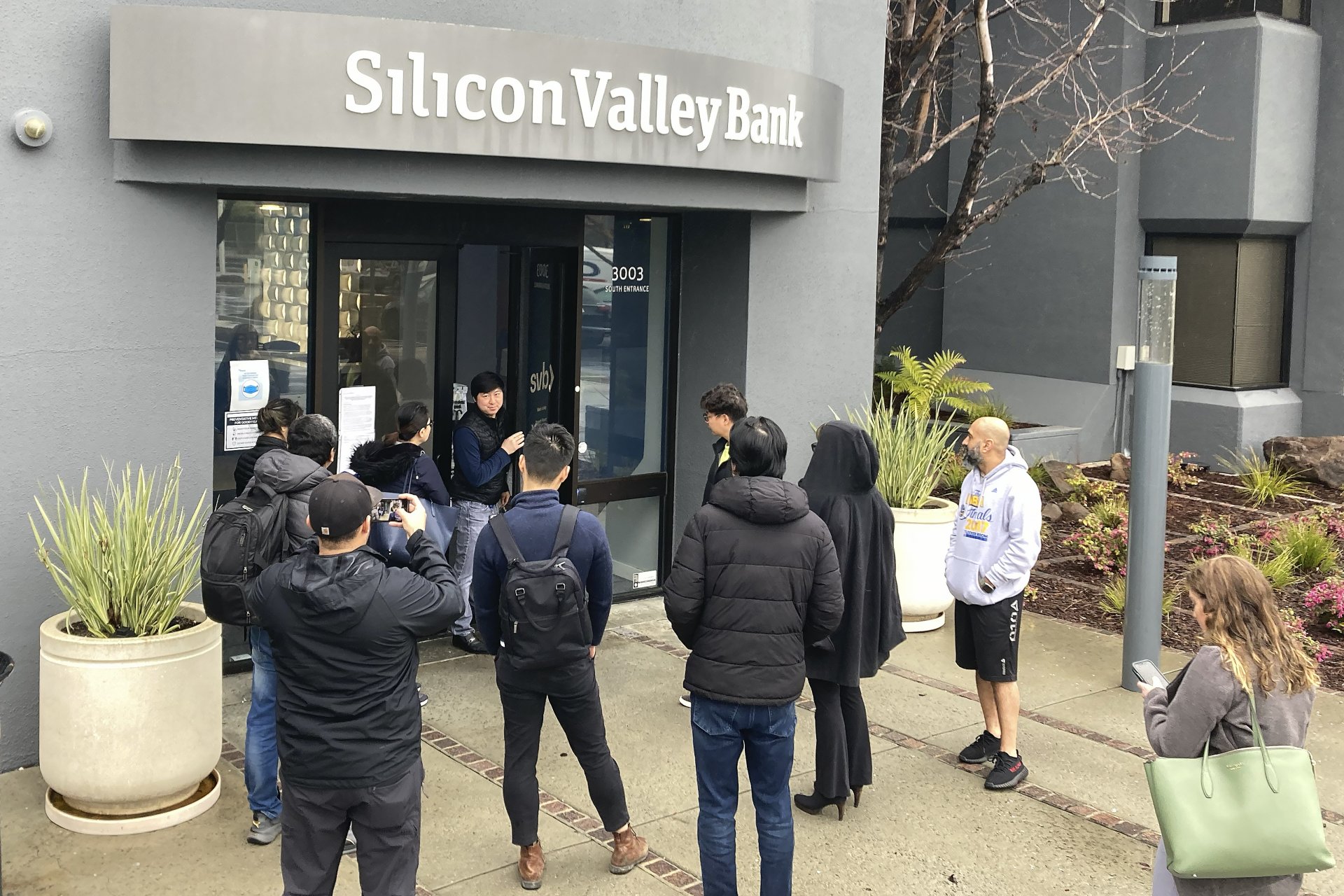 Служител на Silicon Valley Bank говори с чакащи да влязат клиенти в централния офис на банката в Санта Клара, Калифорния