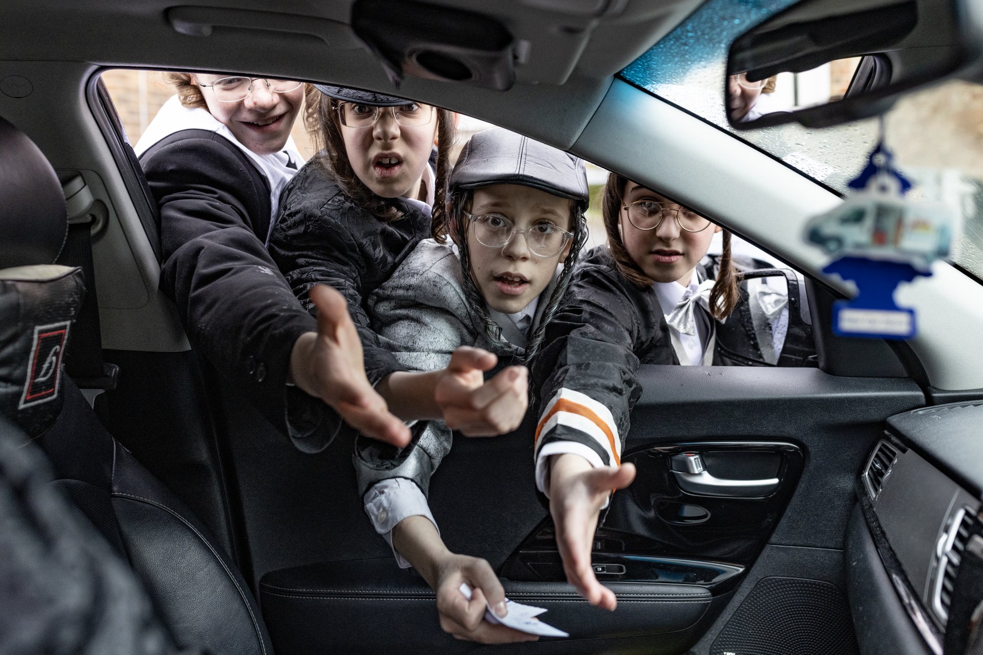  Група православни еврейски момчета се събират около кола, за да се опитат да съберат монети по време на еврейския празник Пурим на 7 март 2023 г. в Лондон, Англия