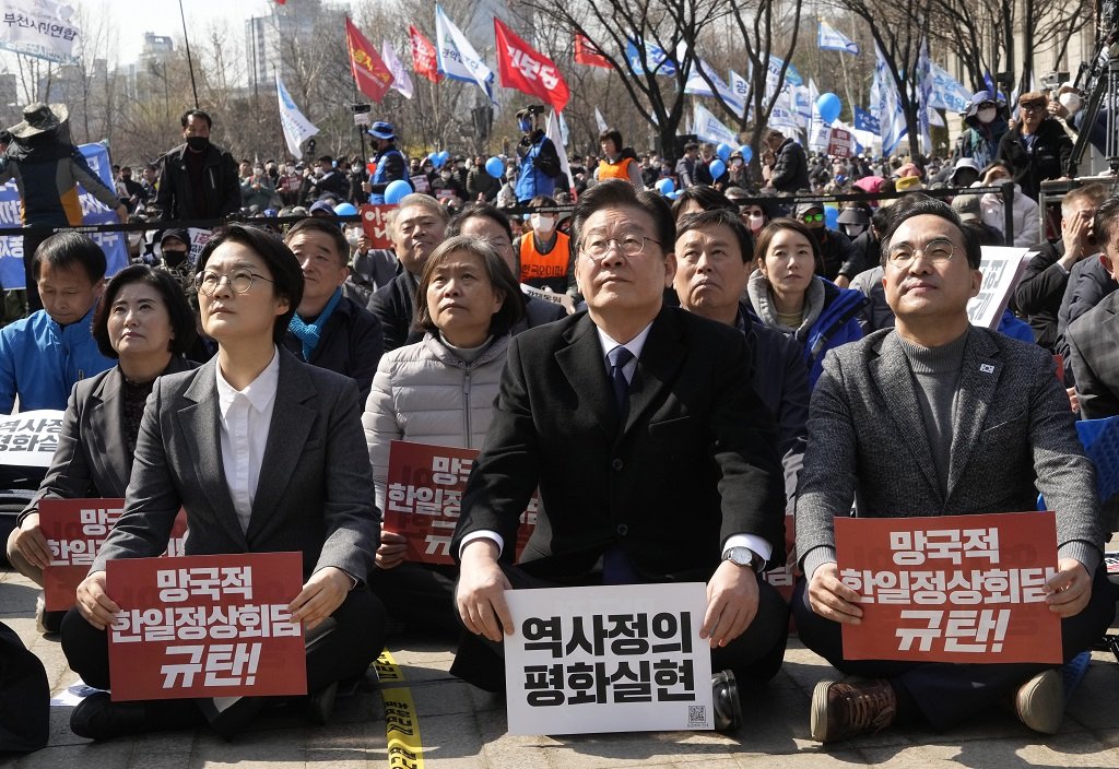 Лидерът на основната южнокорейска опозиционна Демократическа партия Ли Дже Мюн (в средата) в митинг, на който се осъжда срещата на върха на президента Юн Сук Йол с японския премиер Фумио Кишида на 16 март, Сеул, Южна Корея