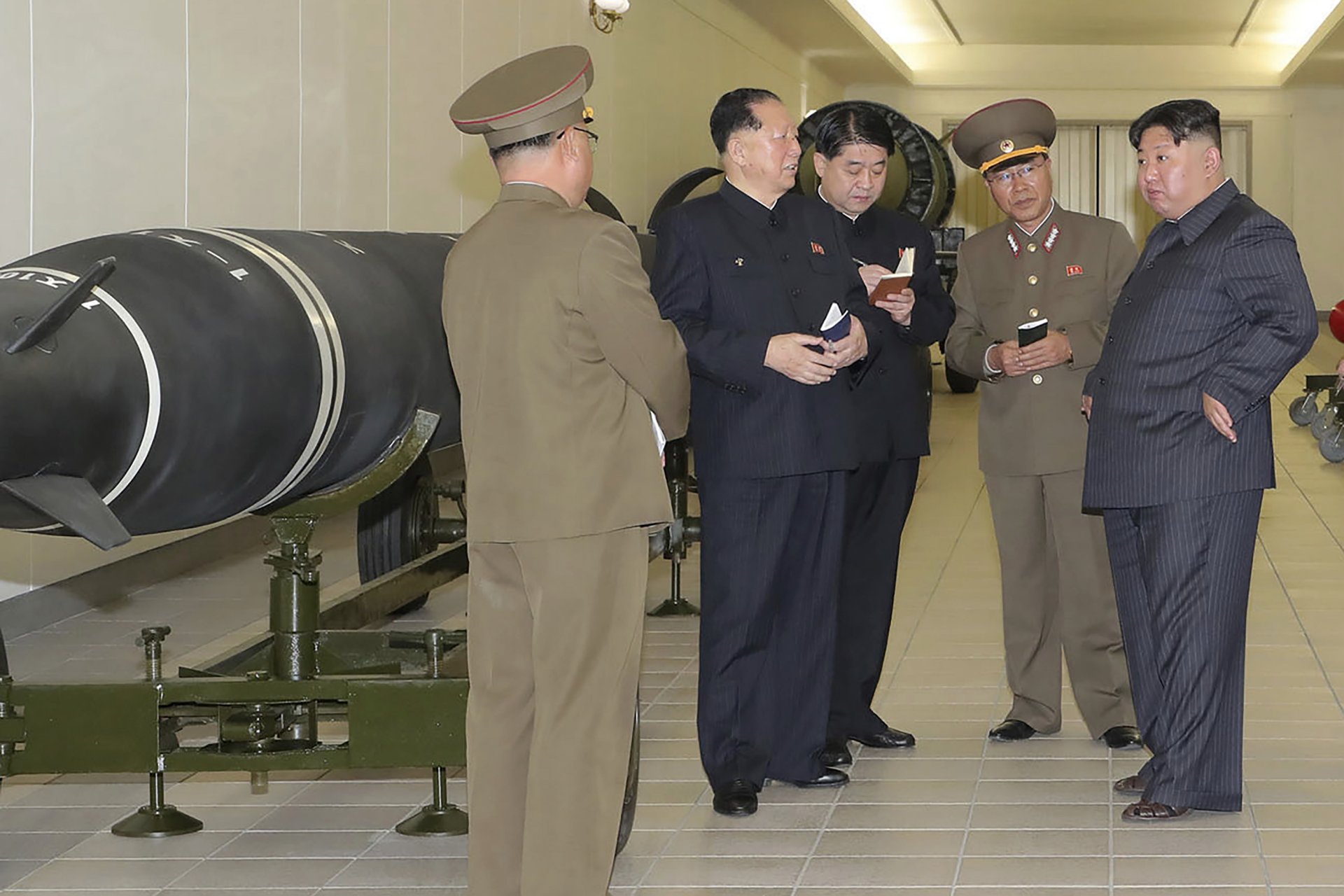 Ким Чен Ун, вдясно, разговоря с военни, които му показват по-малки бойни глави, предназначени за монтиране на ракети или ракетни установки, 27 март 2023 г.