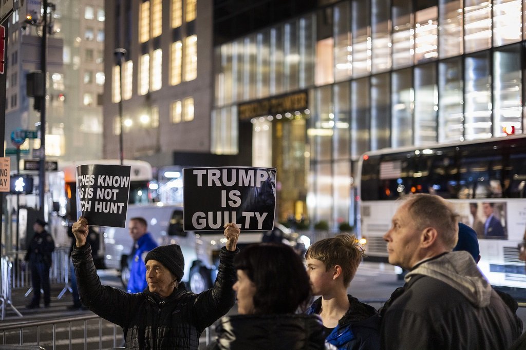 Протестиращ държи плакат пред кулата на Тръмп в Ню Йорк
