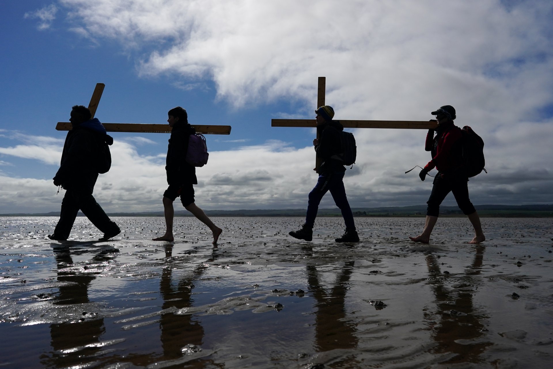 Поклонници носят дървени кръстове, докато вървят по приливната пътека към Линдисфарн по време на последния етап от годишното им поклонение за Разпети петък.