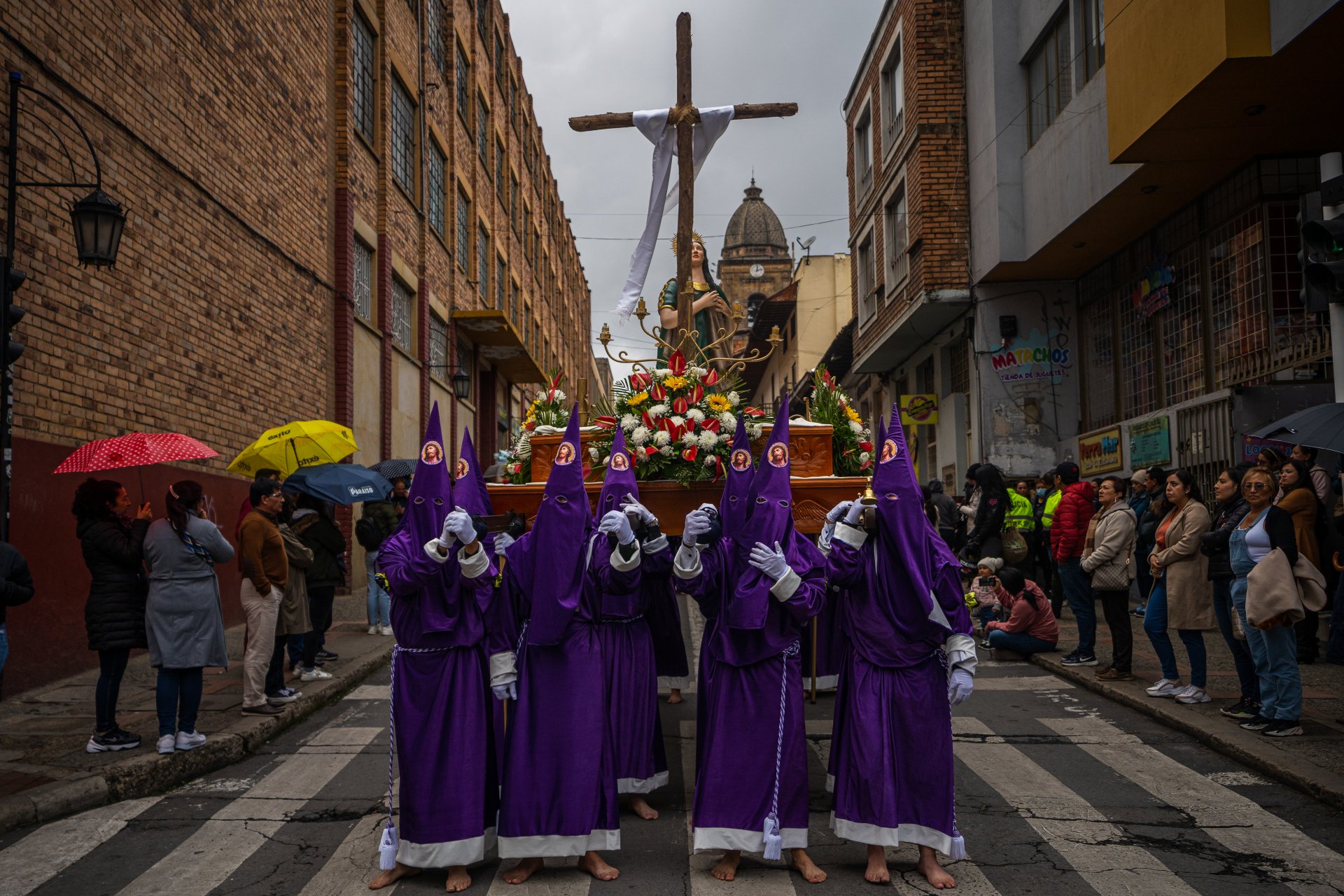 Членове на назарянското братство носят религиозна статуя по време на процесията Санто Сепулкро в покрайнините на столичната катедрала.