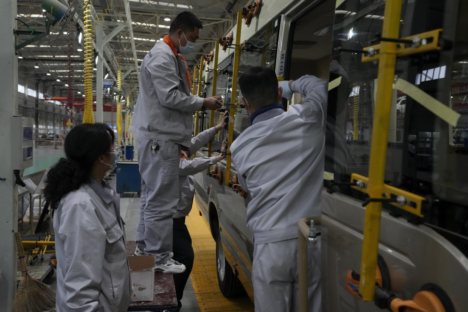 Работници наместват прозоречни панели върху минибуз в китайски завод за дограма, 10 май 2023 г.