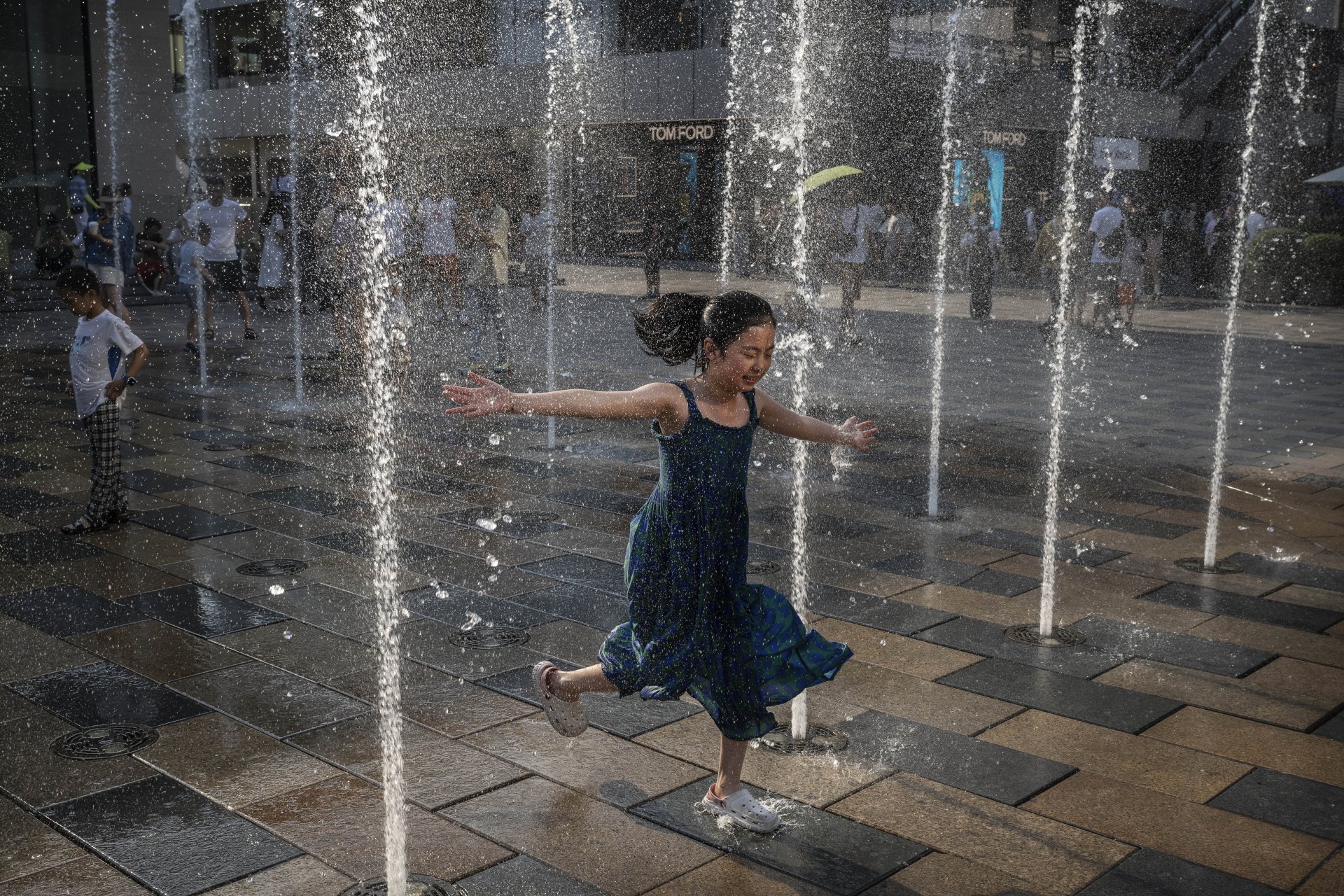Момиче тича през фонтан в търговския център, за да се разхлади по време на горещата вълна. Властите обявиха код Червено за високи температури. 
