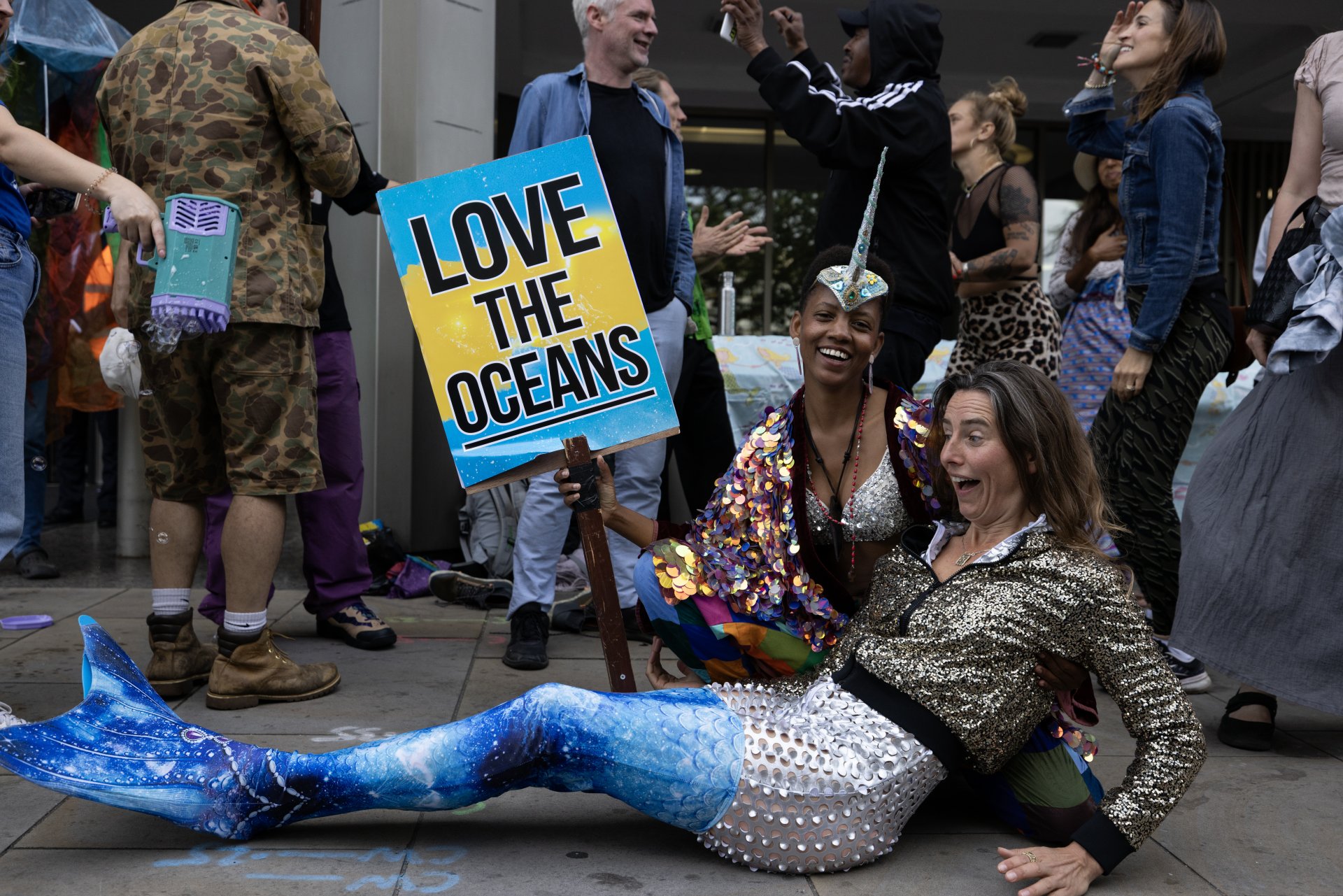 Еко активисткa, oблечен като русалка, докато участва в "сутрешен рейв" пред централата на Международната морска организация в първия ден от конференцията на ООН за корабоплаването и океаните. 