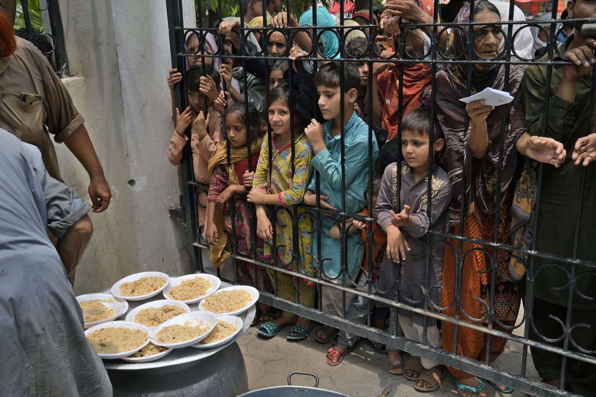Жени и деца чакат за безплатна храна в Лахор, Пакистан
