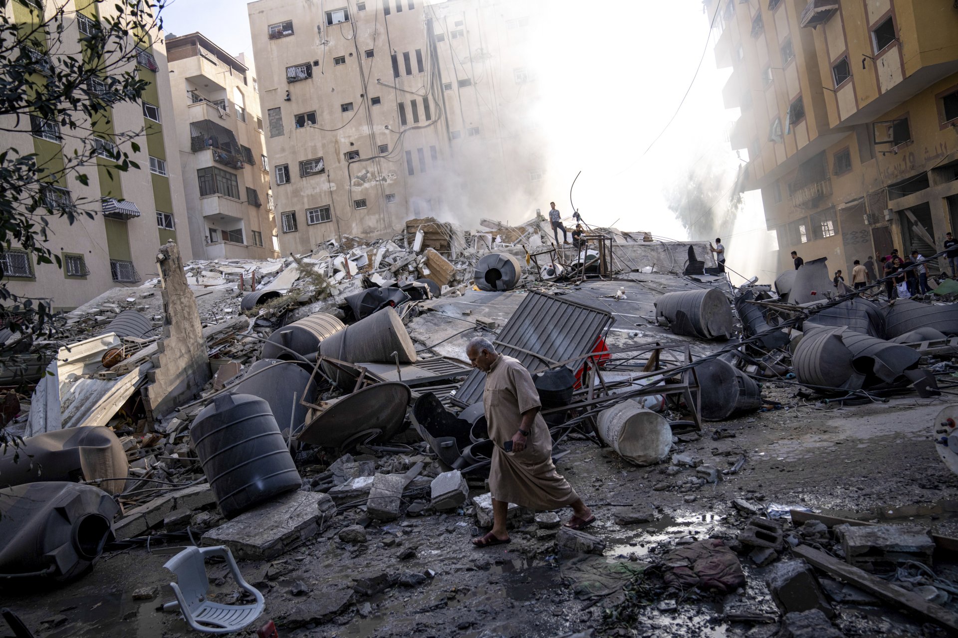 Палестинците оглеждат развалините на сграда, след като е била ударена от израелски въздушен удар в град Газа