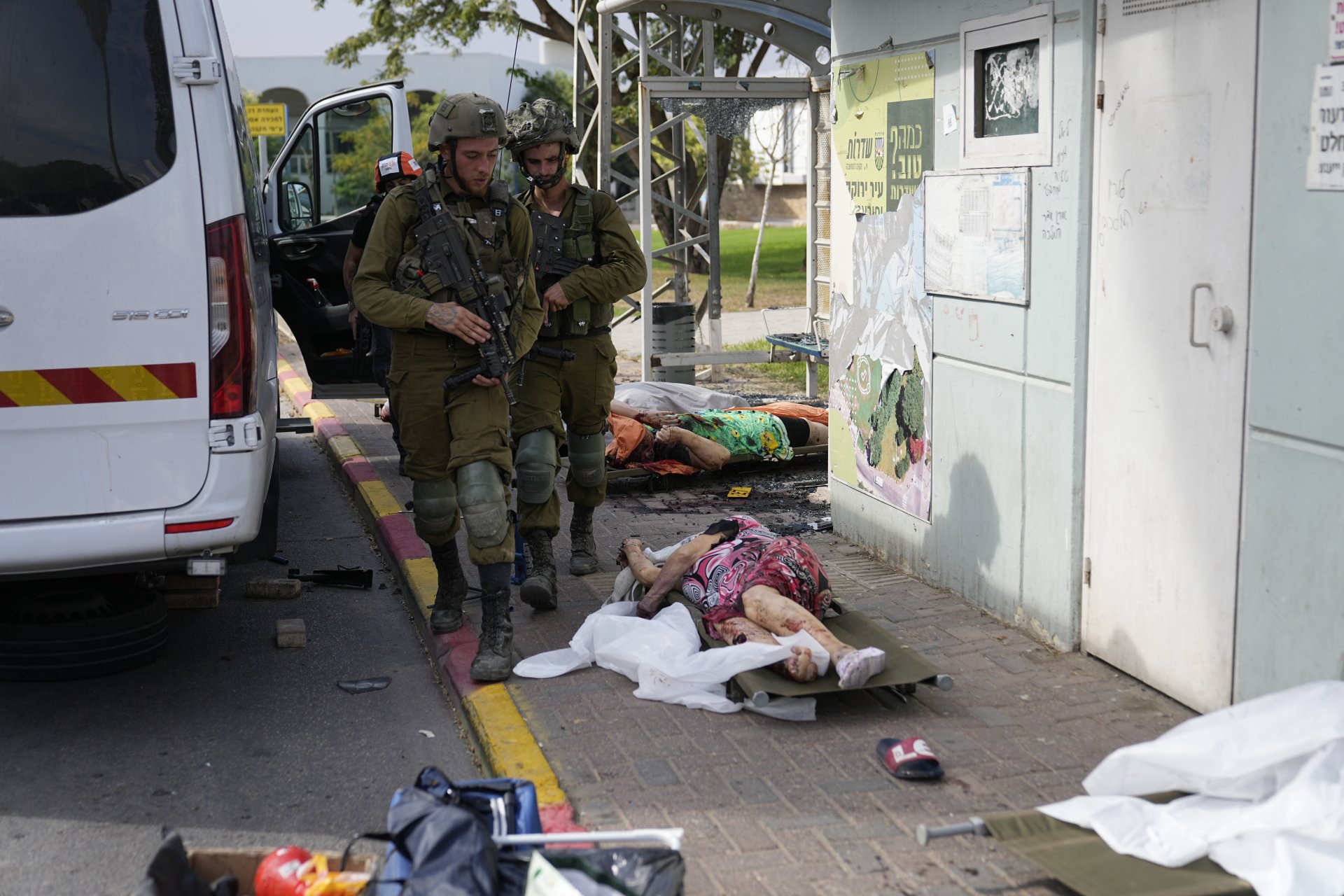 Израелски войници минават покрай цивилни, убити от палестински бойци в Сдерот, Израел, в събота, 7 октомври 2023 г.