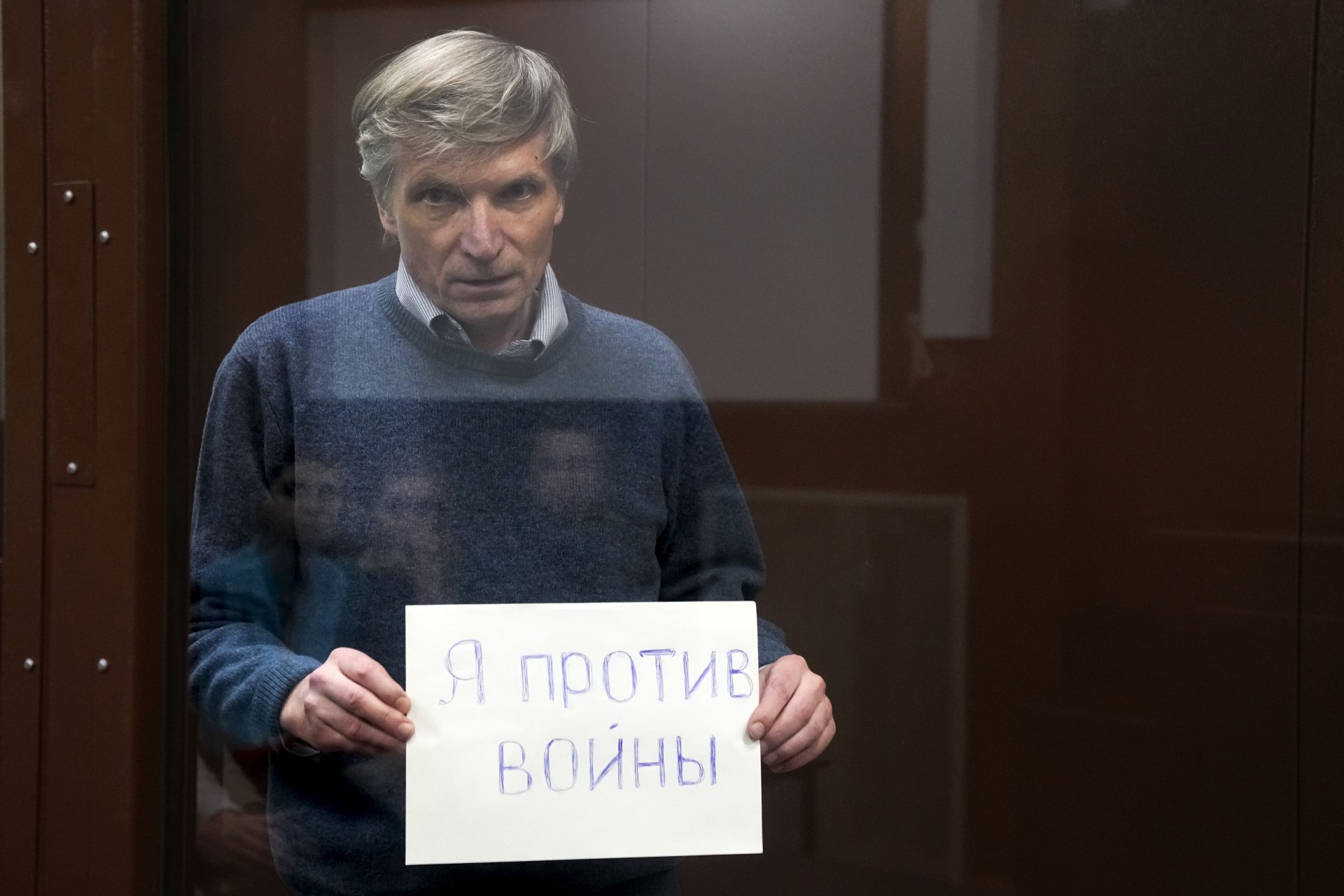 Поставен в клетка в съдебната зала, Алексей Горинов държи надпис "Аз съм против войната" на съдебно заседание по делото срещу него в Москва на 21 юни 2022 г. 