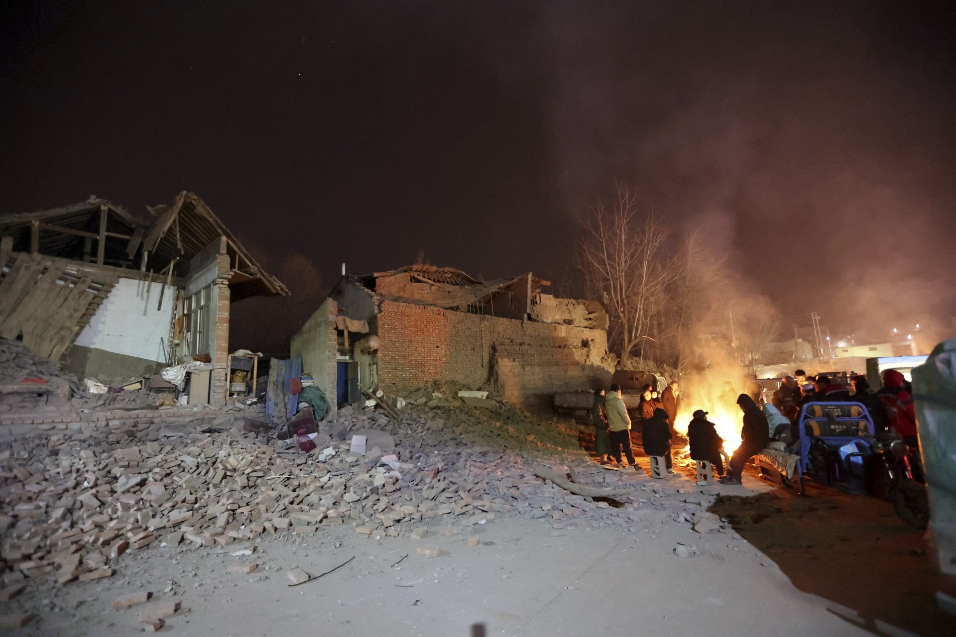 Жителите се събират близо до огън, за да се стоплят в мразовити условия след земетресение в село Кандиао в окръг Джишишан в северозападната китайска провинция Гансу