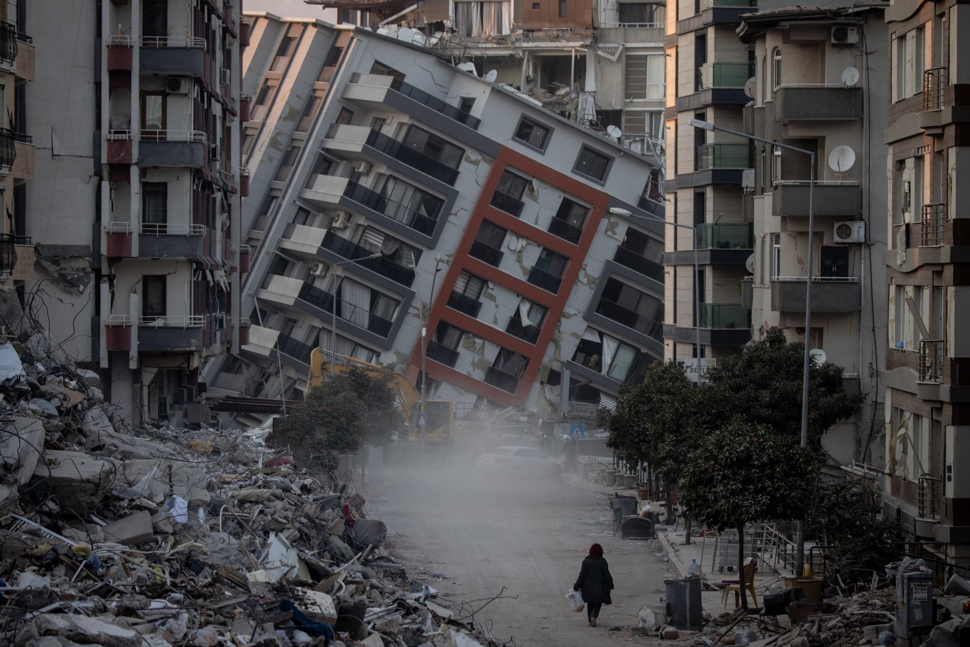 Жена върви по улица сред разрушени сгради. Земетресенията причиниха мащабни разрушения в Южна Турция и Северна Сирия и убиха повече от 40 000 души. 