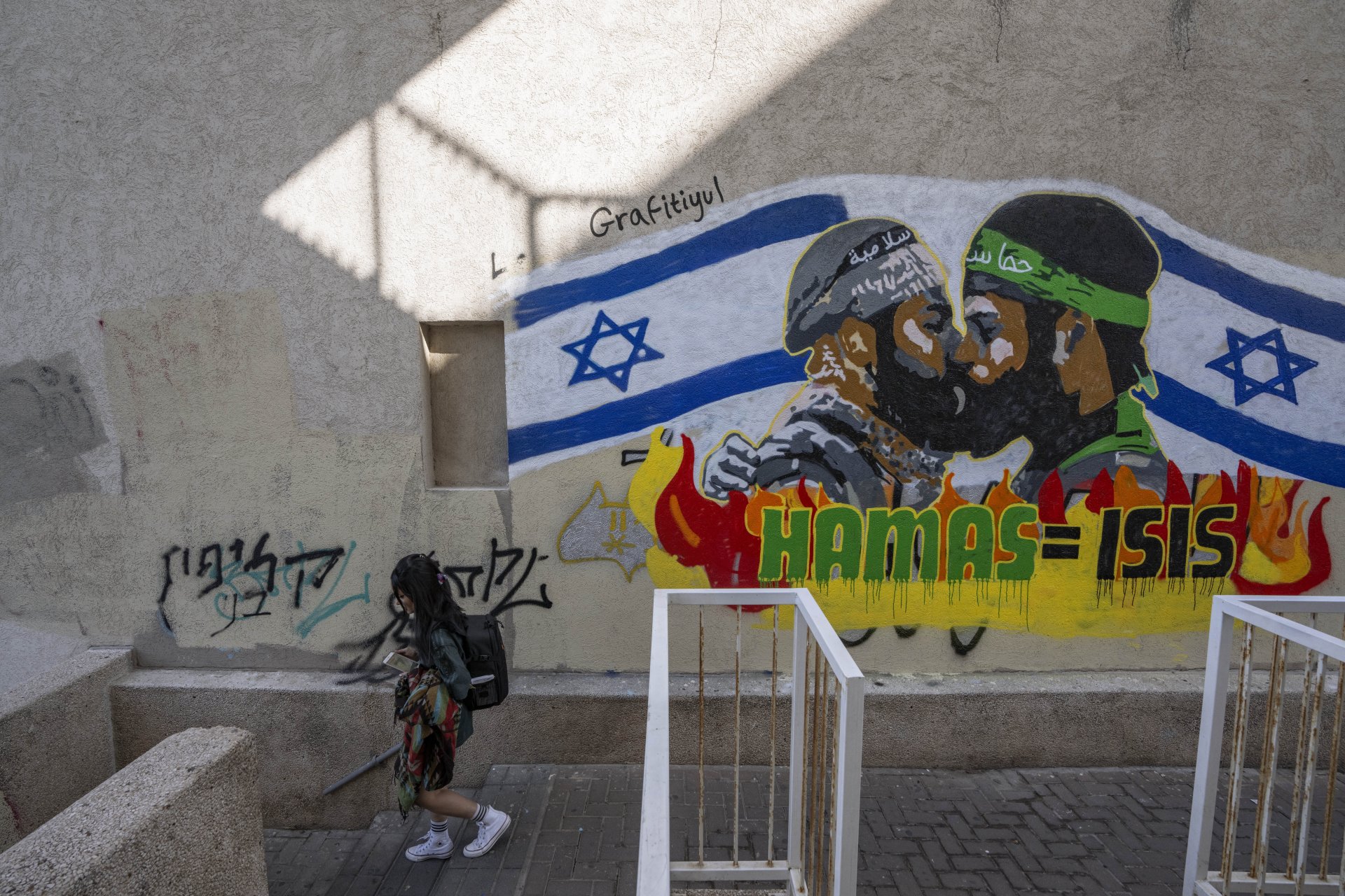  Жена минава покрай графит на стена в Тел Авив, който гласи "Хамас е равен на "Ислямска държава"