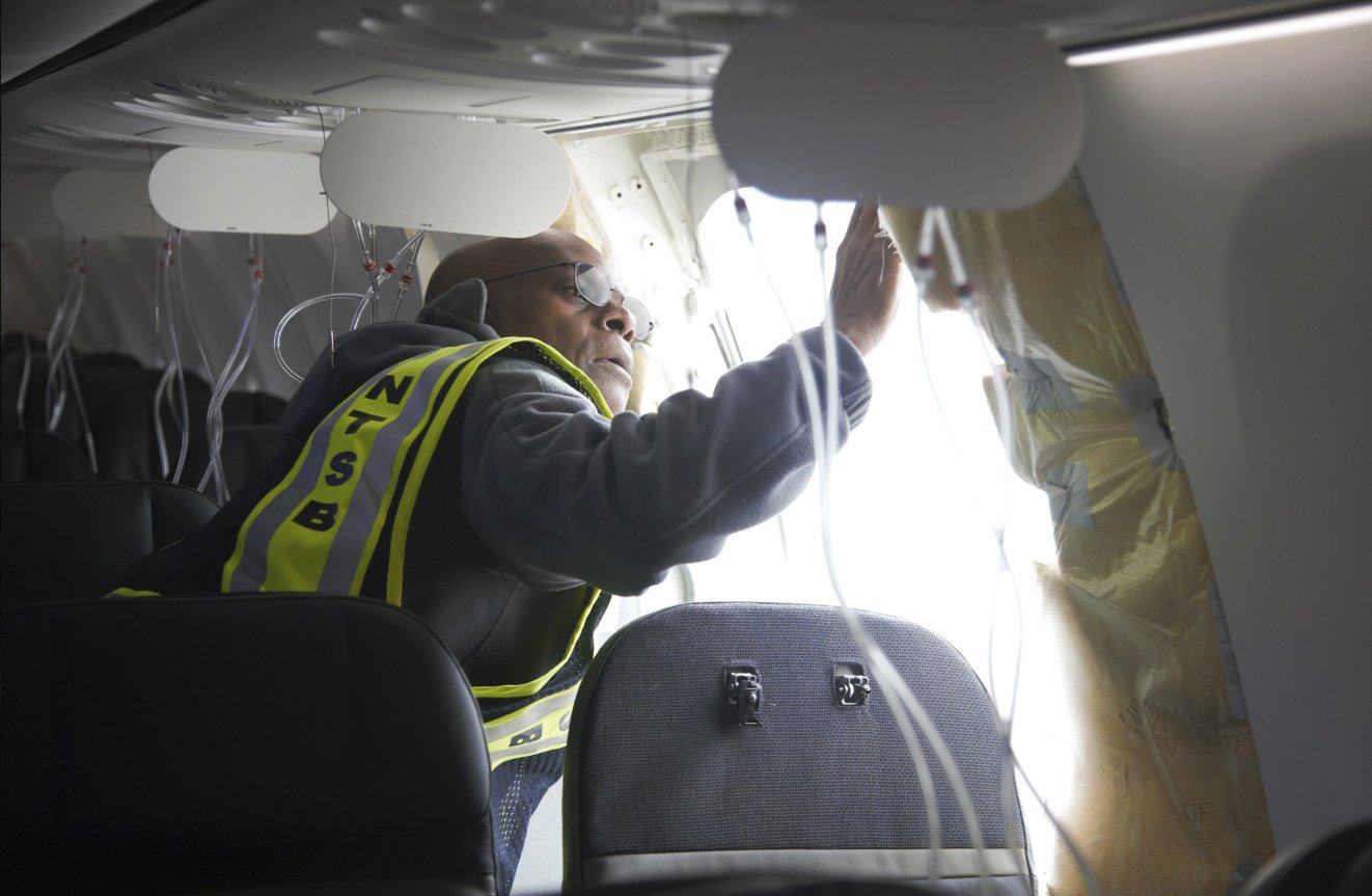 На тази снимка, публикувана от Националната агенция по безопасност на транспорта, главният следовател Джон Ловел изследва зоната на фюзелажа на полет 1282 на Alaska Airlines в неделя, 7 януари 2024 г., в Портланд, Орегон