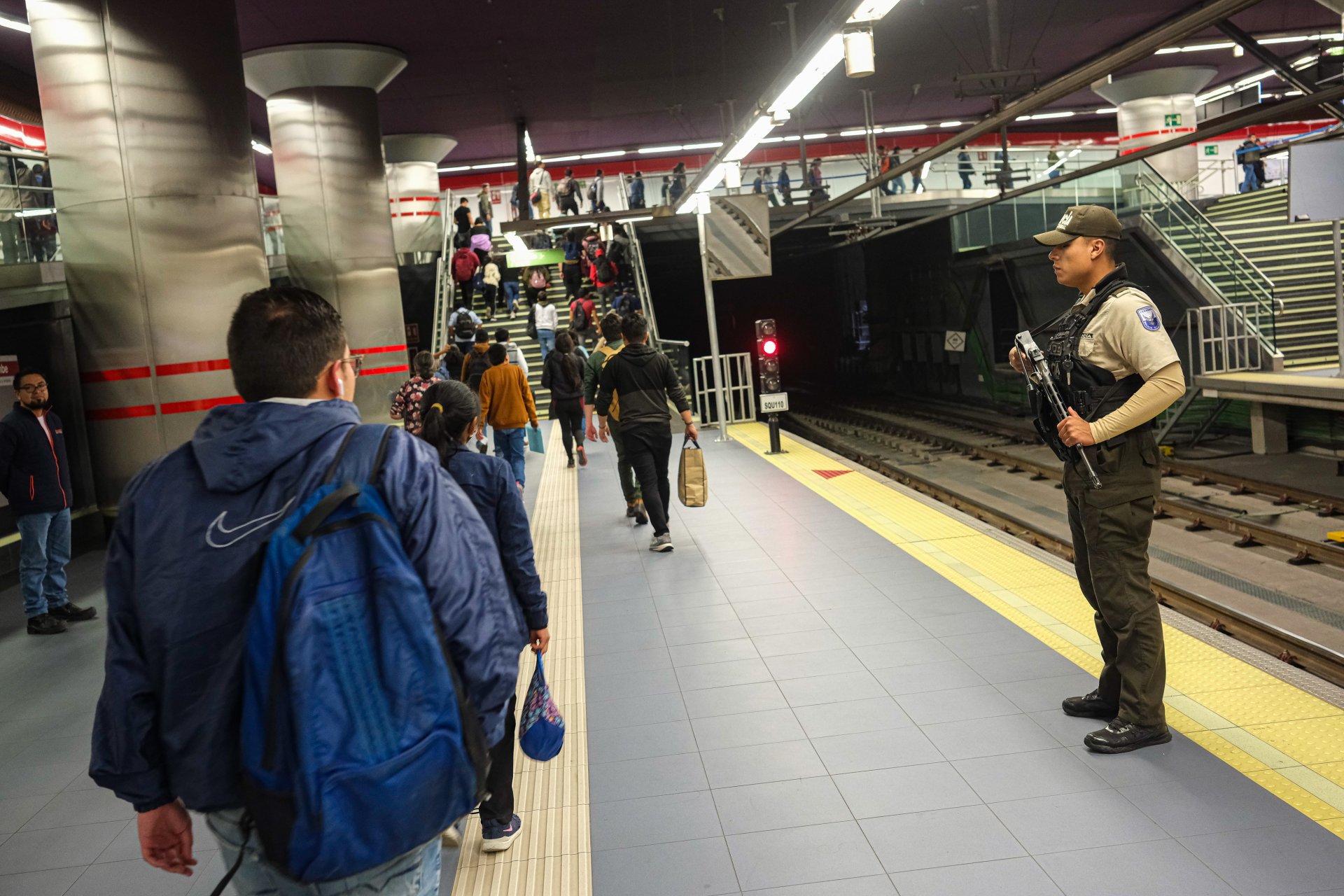 Полицейски служители стоят на стража, докато пътуващите минават покрай метростанция на 10 януари 2024 г. в Кито, Еквадор. 