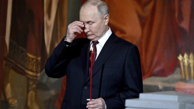Путин облечен в тъмен костюм с бяла риза и тъмночервена
