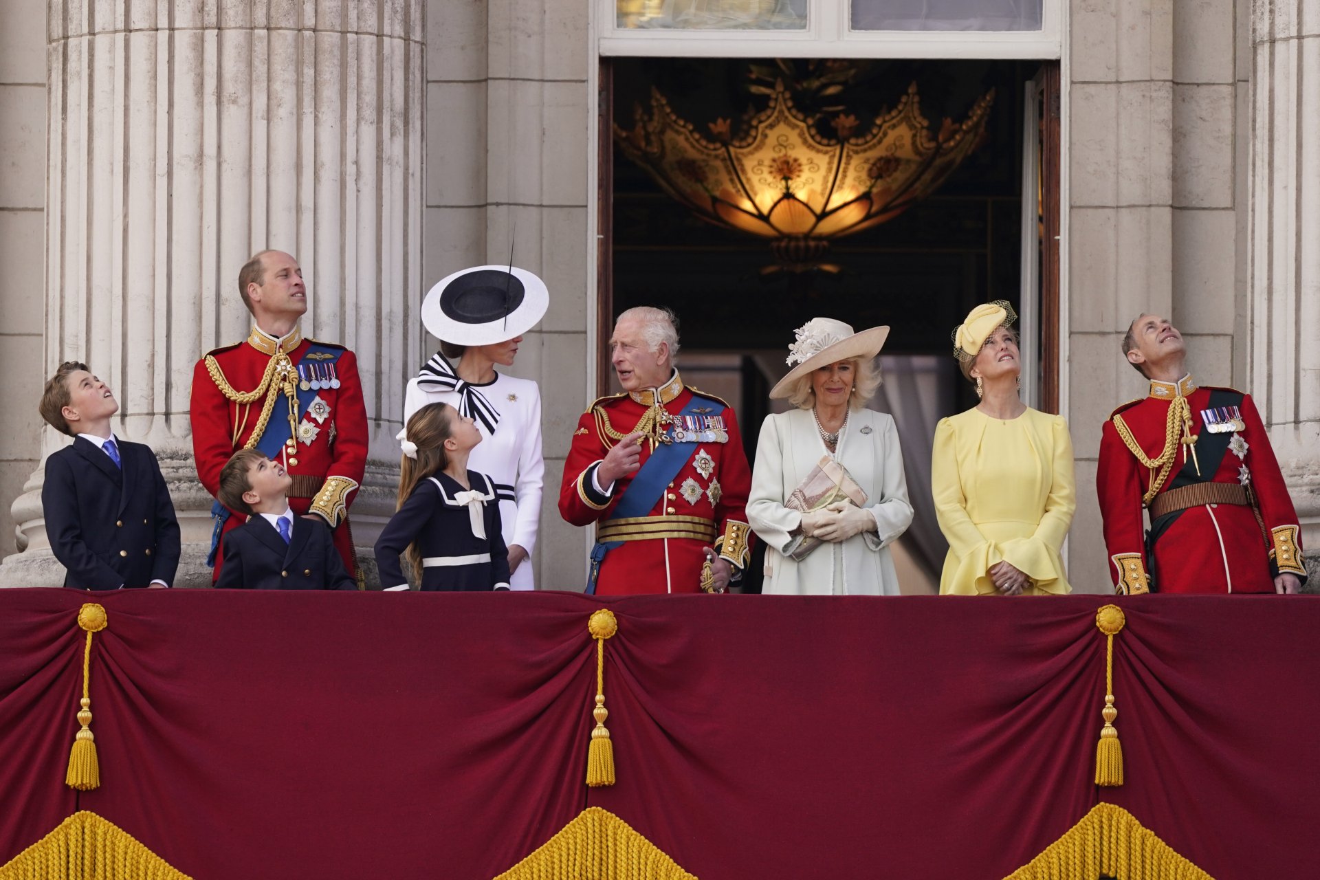 Британският крал Чарлз III, в центъра с кралица Камила, принц Джордж, вляво, принц Уилям, принц Луис, принцеса Шарлот, Кейт, принцесата на Уелс, Софи, херцогинята на Единбург, и принц Едуард на балкона в Бъкингамския дворец след церемонията Trooping the C