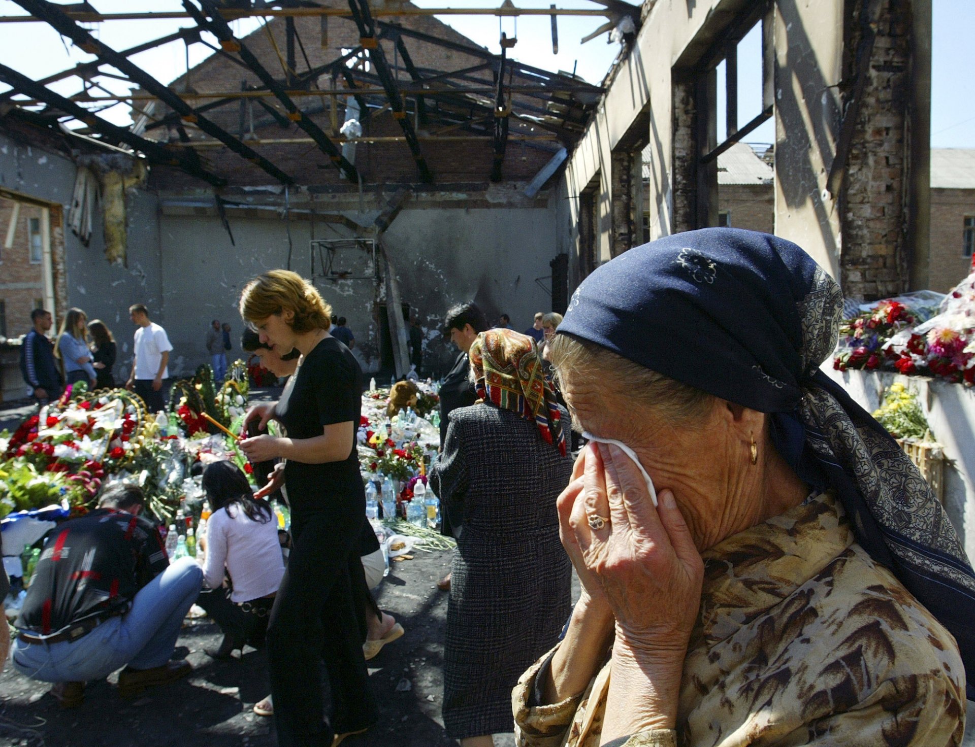 Близки и роднини плачат и оставят цветя на 9 септември 2004 г. в разрушения физкултурен салон на Първо училище