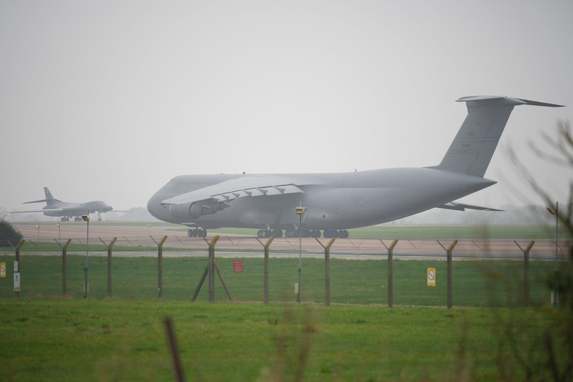 Военнотранспортен С-5 Galaxy рулира покрай бомбардировач B1 Lancer.